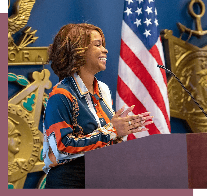 A woman standing at a podium with her hands up.