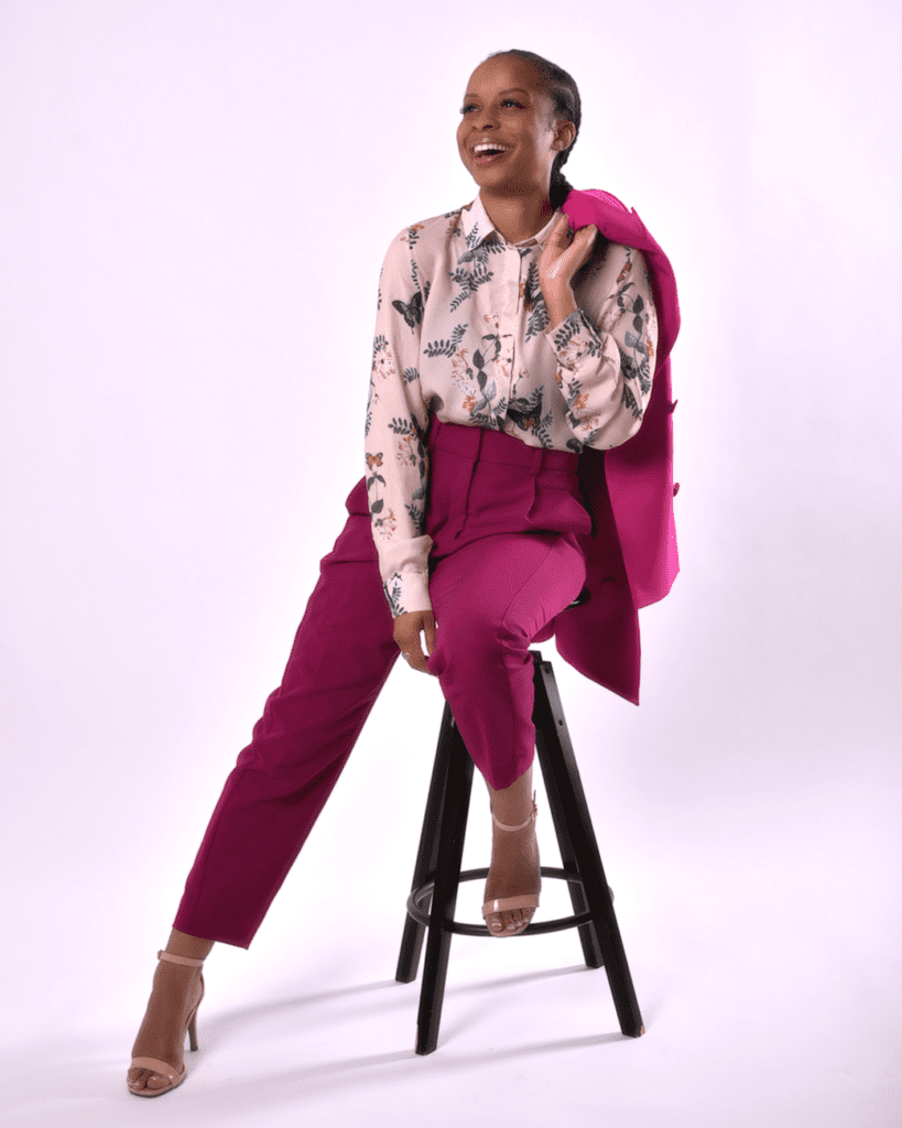 A woman sitting on top of a stool wearing pink pants.